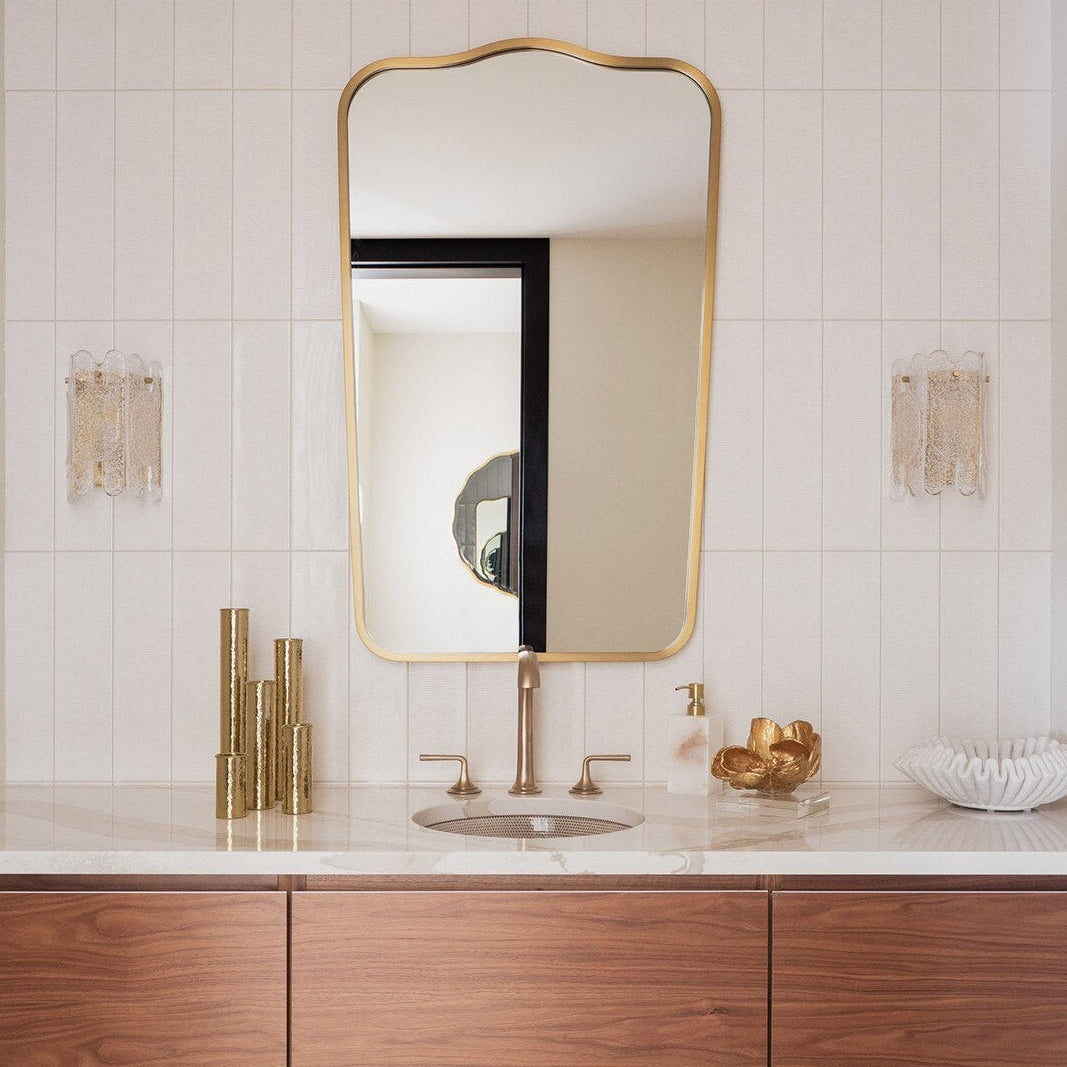 Bathroom with wooden vanity, sink, and gold-framed mirror.