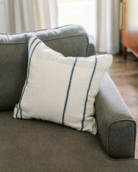 White pillow with blue stripes on a gray sofa