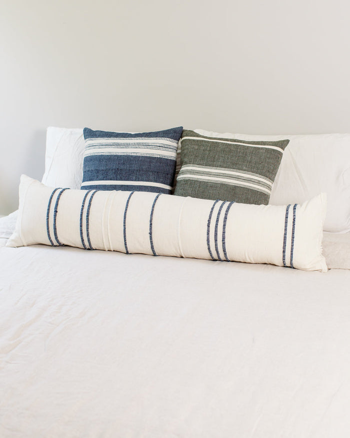 Set of striped pillows on a bed with a neutral background