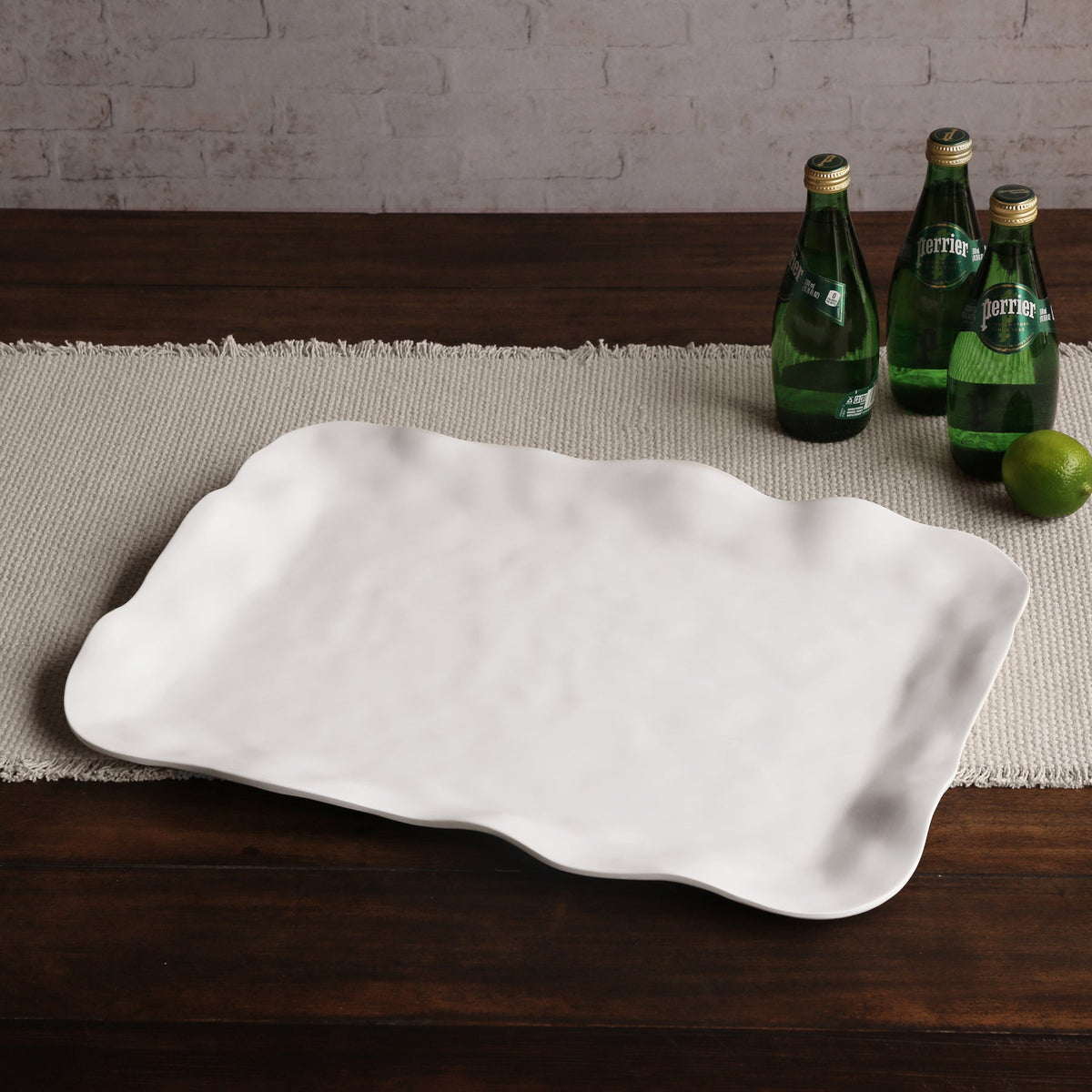 White ceramic platter on a wooden table with green bottles and a lime in the background.