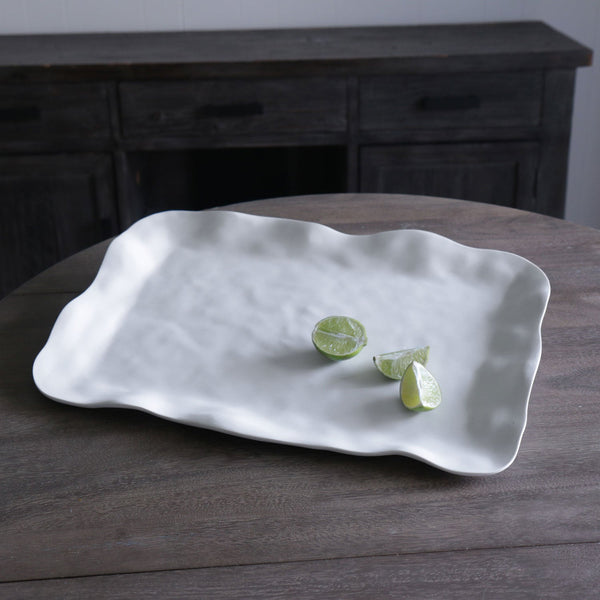 White ceramic dish with wavy edges on a wooden table