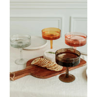 Cocktail glasses with different colored liquids on a wooden board with crackers.