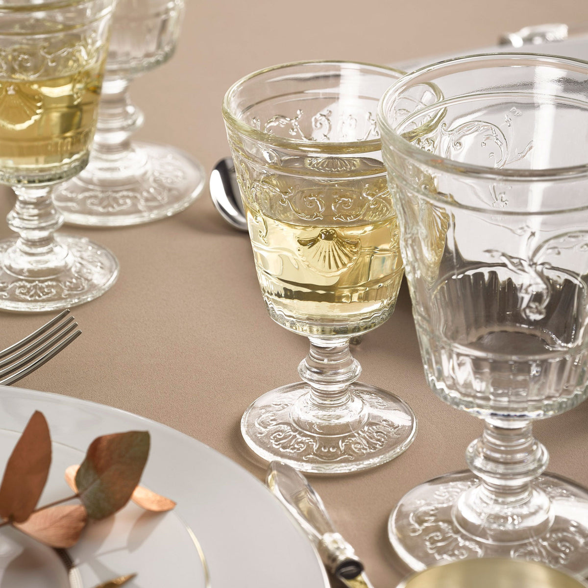 Decorative glassware with liquid on a beige tablecloth