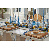 Acacia wood scalloped cutting boards on a dining table with blue candles and decorative gourds.