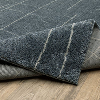 Alton Blue & Beige casual rug, power-loomed polyester with subtle grid pattern, partially rolled on wood floor.