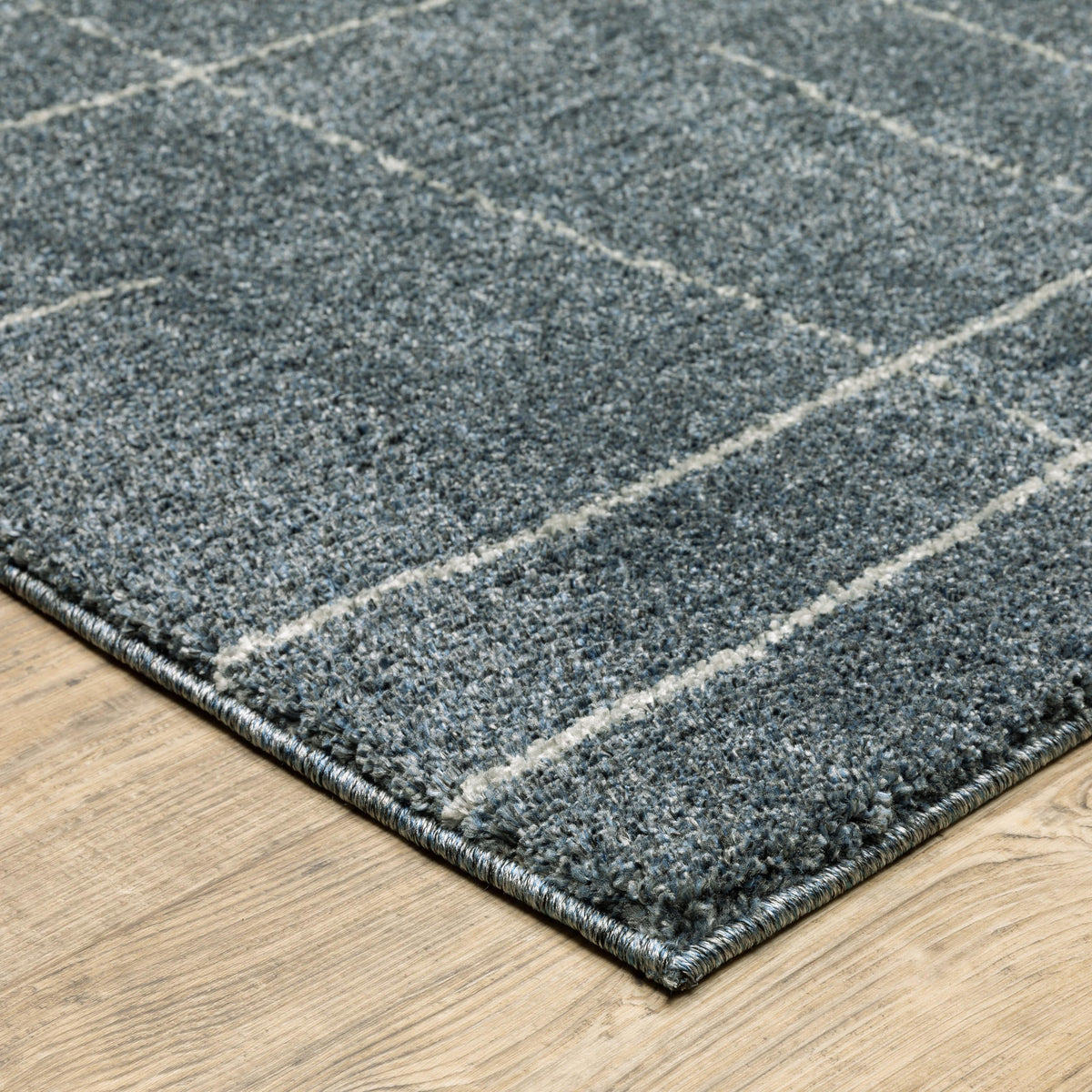 Alton Blue & Beige Casual Rug, power-loomed polyester with a subtle grid pattern on a light wood floor.