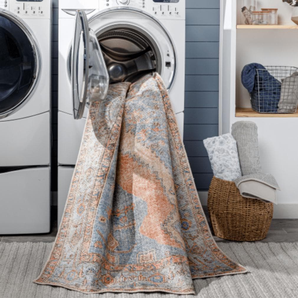 Amelie Blue & Coral Chenille Washable Rug with traditional design, partially in a washing machine.