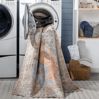 Amelie Blue & Coral Chenille Washable Rug with traditional design, partially in a washing machine.