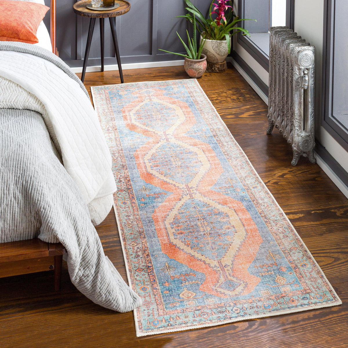 Amelie Blue & Coral Chenille Washable Rug with traditional design on a wooden floor.