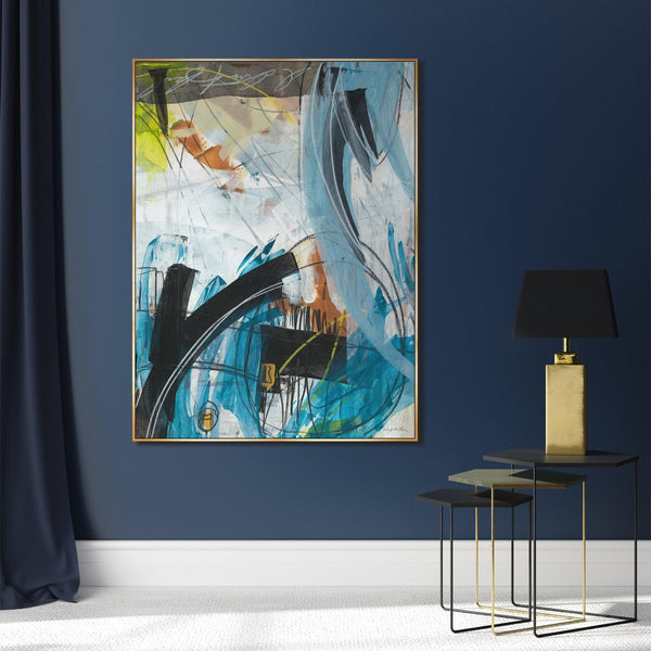 Abstract giclee canvas painting with blue, black, white, and orange brushstrokes in a gold frame on a navy wall.