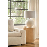 Arlo white ceramic table lamp with rounded base and natural linen shade on a wood side table.