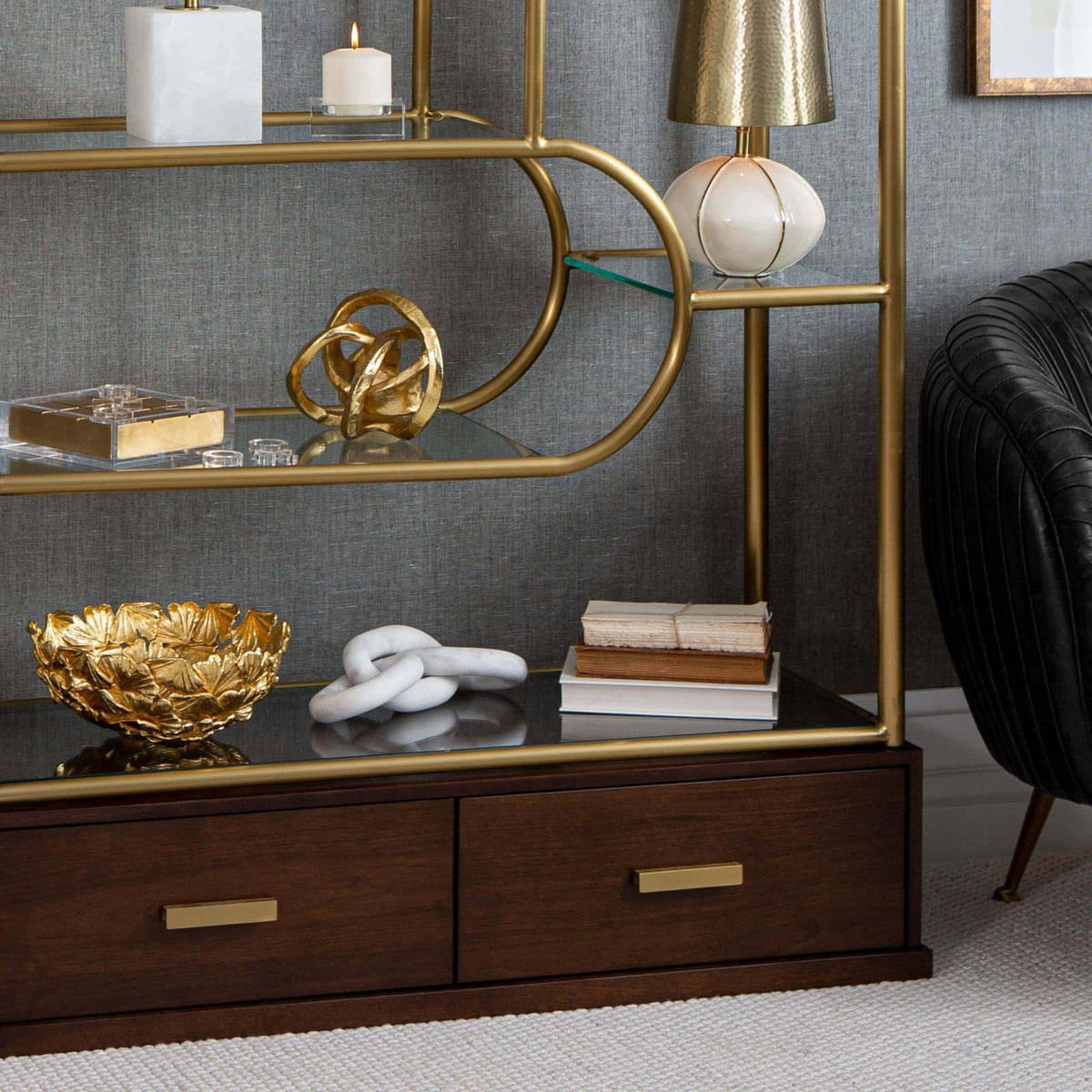 White marble chain accent piece on a dark shelf, part of a stylish gold and wood display.