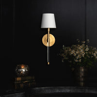 Auburn brass and crystal sconce with a circular gold leaf backplate, clear crystal tail, and white linen shade.