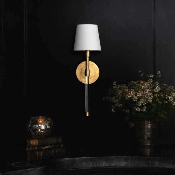 Auburn brass and crystal sconce with a circular gold leaf backplate, clear crystal tail, and white linen shade.