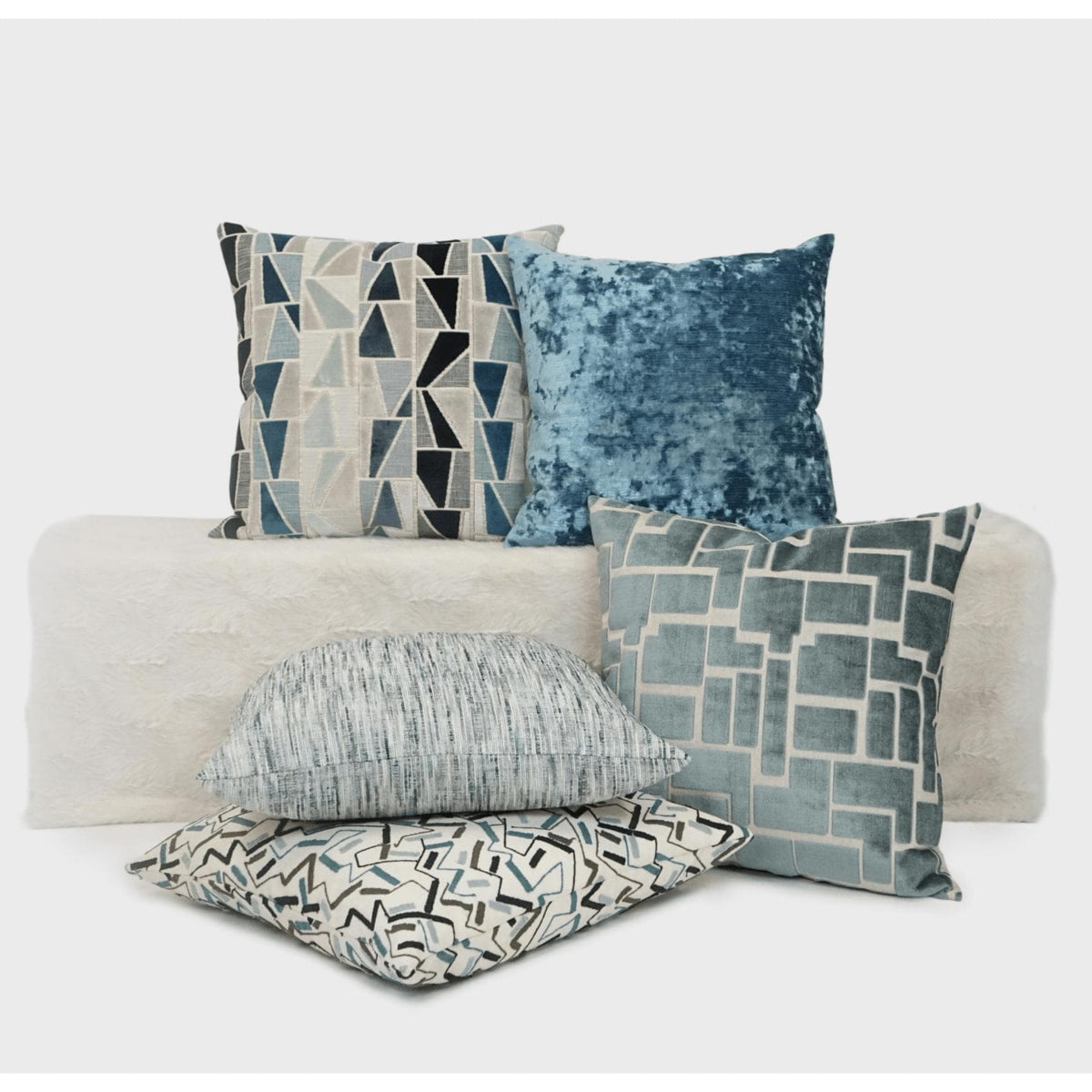 Aura Geometric Throw Pillow in blue and gray with other luxury accent pillows.