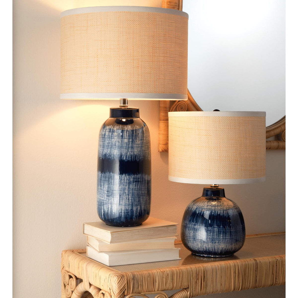 Indigo blue and white batik table lamps with textured beige shades on a rattan console.