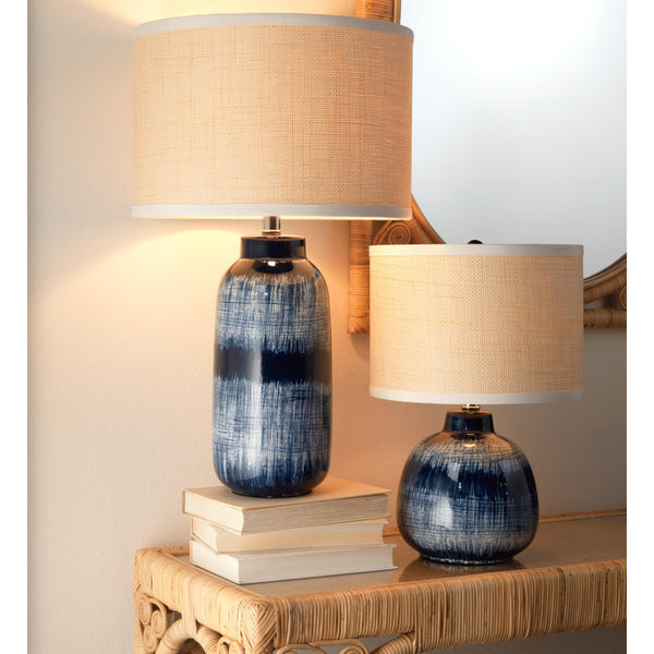 Indigo blue and white batik table lamps with textured beige shades on a rattan console.