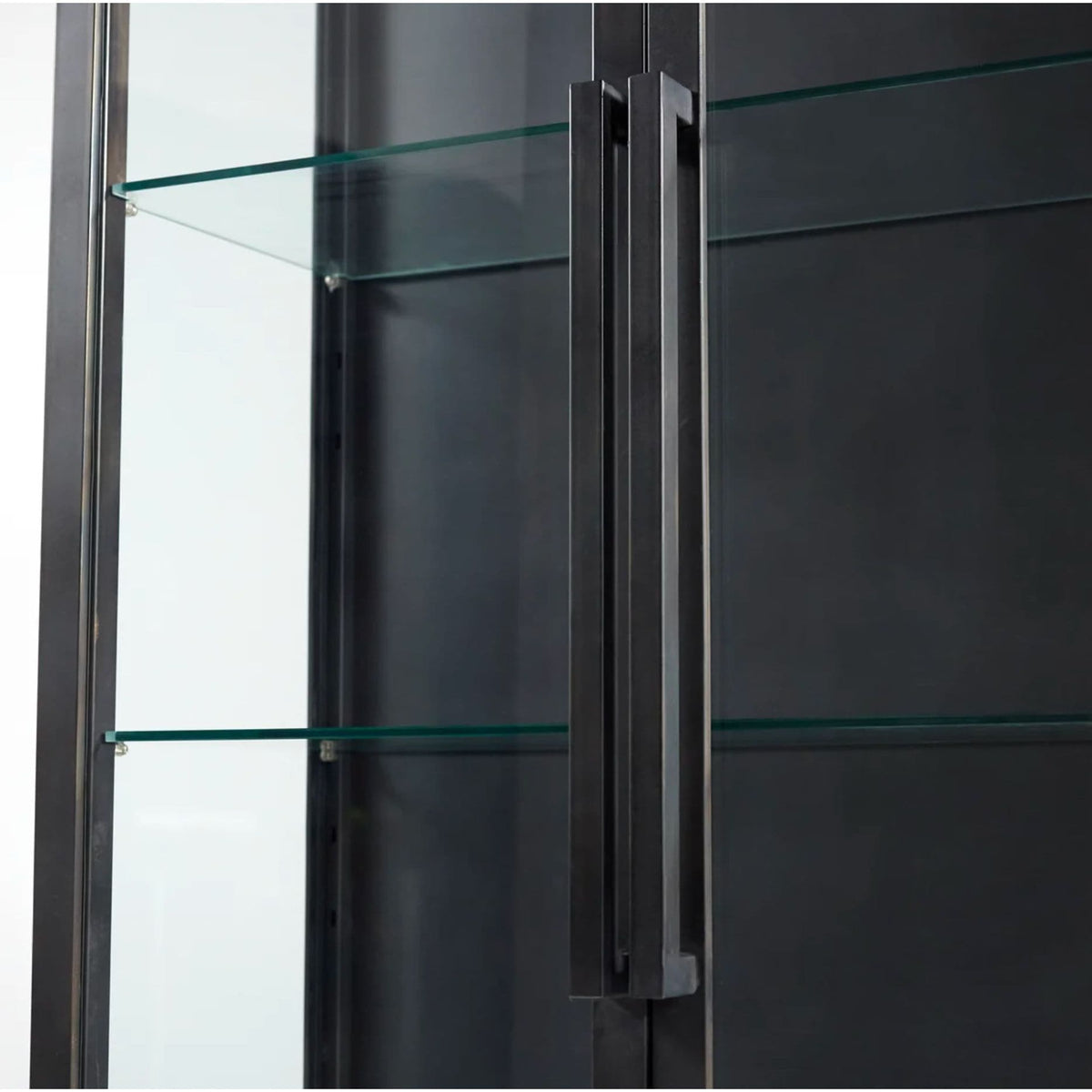 Black iron curio cabinet with glass shelves and a long, dark handle.