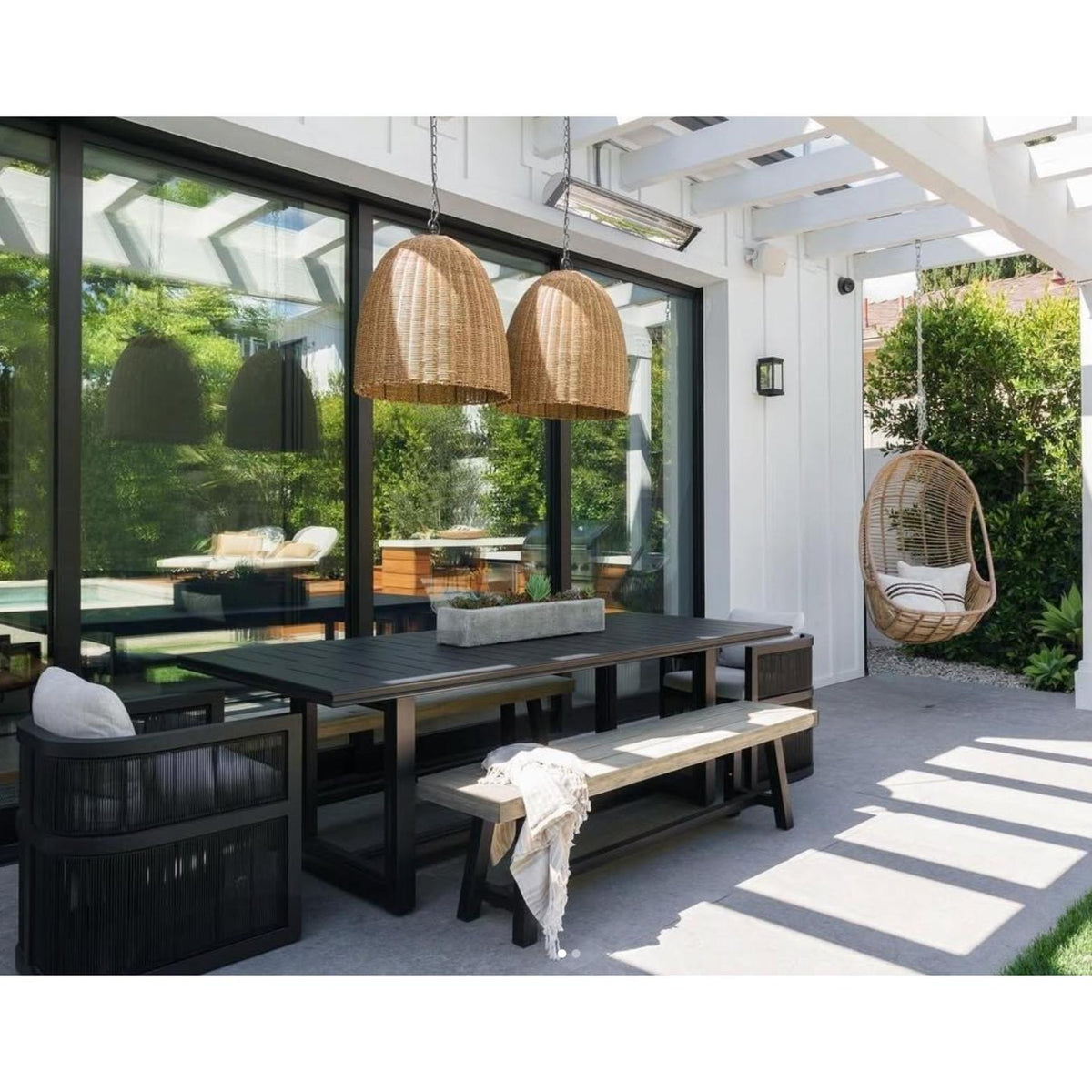 Two large weathered natural rattan-like Beehive outdoor pendant lights hang over a patio dining table.