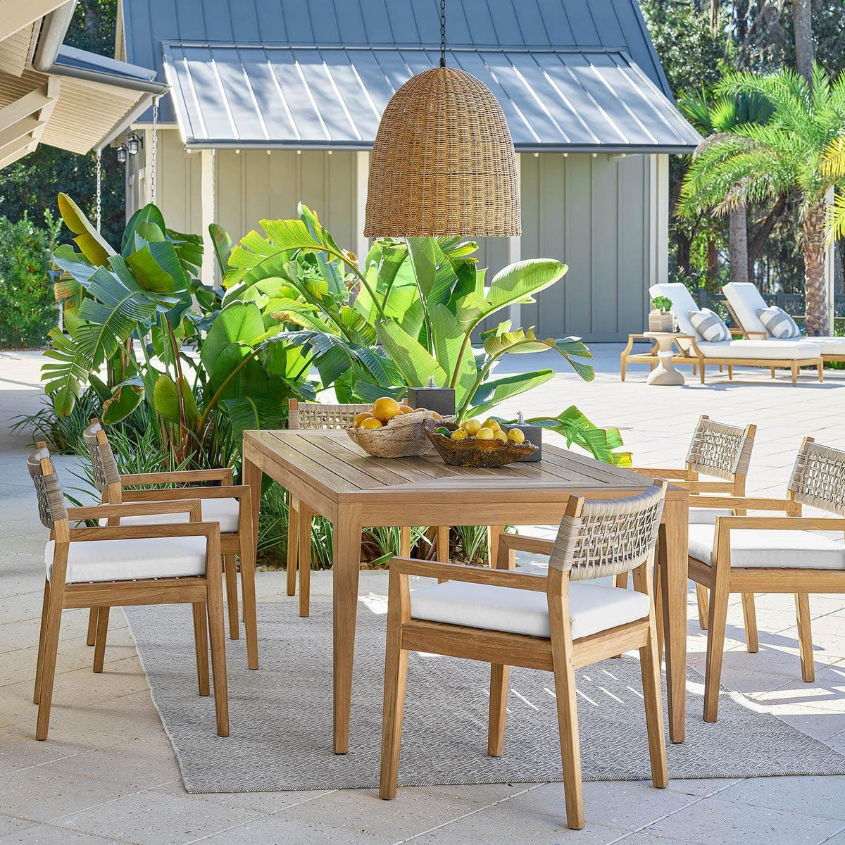 Large weathered natural rattan-like beehive outdoor pendant light hanging over a wooden dining set.