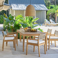 Large weathered natural rattan-like beehive outdoor pendant light hanging over a wooden dining set.