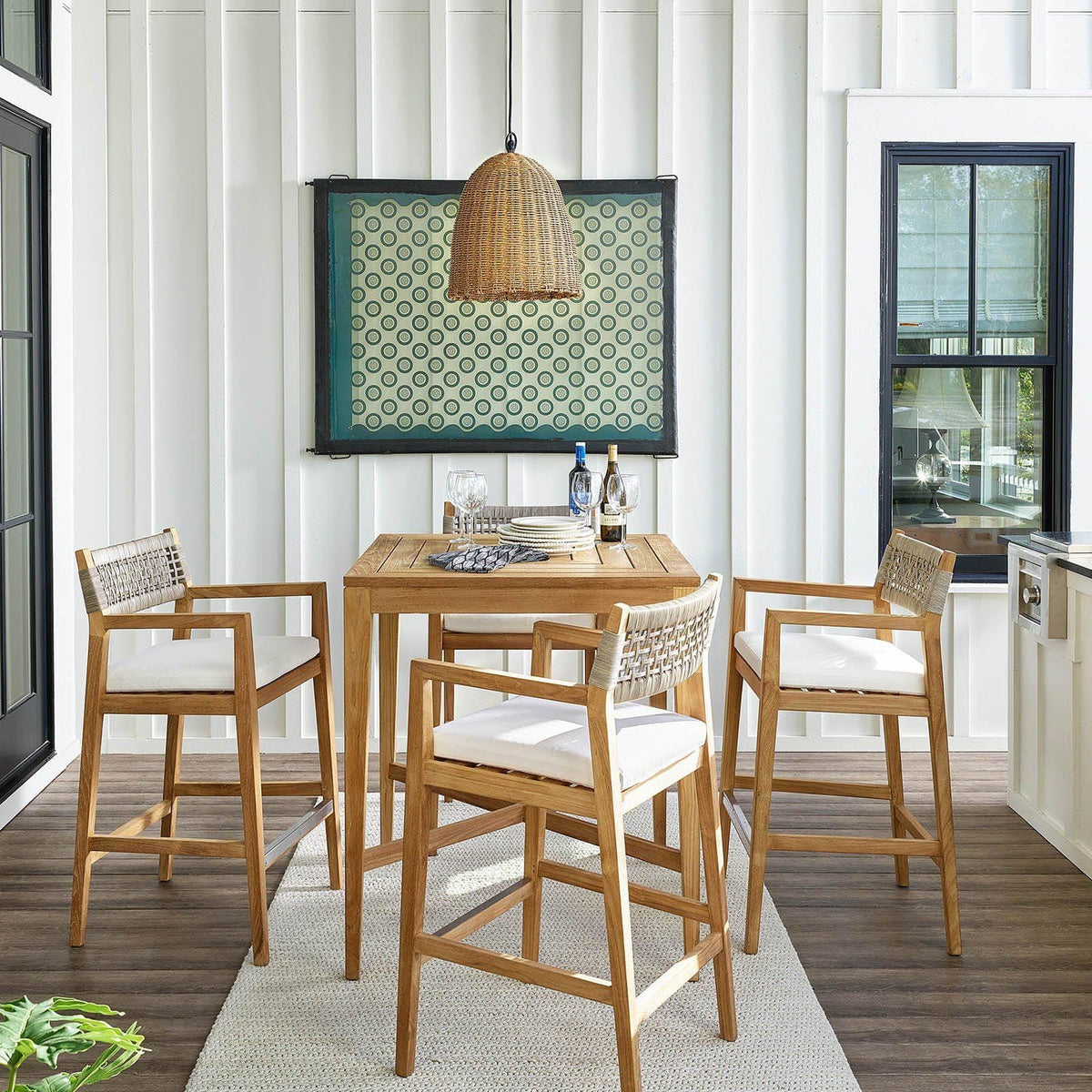Beehive outdoor pendant with a natural rattan-like woven domed shade hanging over a wooden patio dining set.
