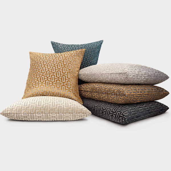 Stack of Bergman decorative throw pillows in gold, cream, grey, brown, and teal with a geometric pattern.