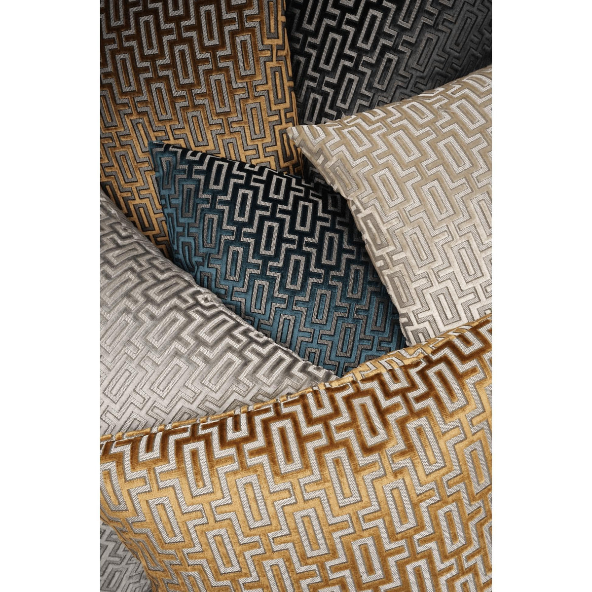 A stack of Bergman decorative throw pillows in various colors: gold, teal, black, gray, and beige, all featuring a geometric maze pattern.