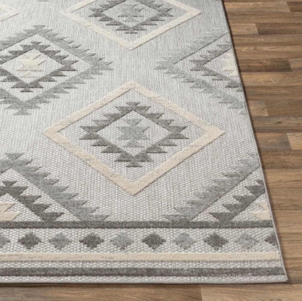 Big Sur Gray Cream indoor/outdoor rug with geometric diamond pattern on wood floor.