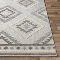 Big Sur Gray Cream indoor/outdoor rug with geometric diamond pattern on wood floor.