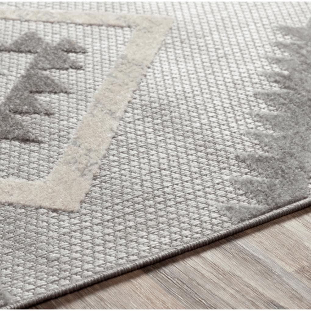 Big Sur Gray Cream indoor/outdoor polypropylene rug with geometric patterns on a wooden floor.