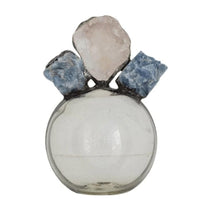 Round clear glass bottle with a light pink geode and two blue calcite pieces on top.
