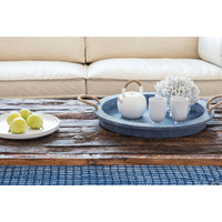 Blue faux rattan serving tray with jute rope handles, holding a white teapot and cups on a rustic wood table.