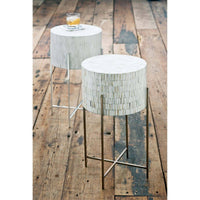 Bone drum table with intricate inlaid bone and polished nickel legs on a wooden floor.