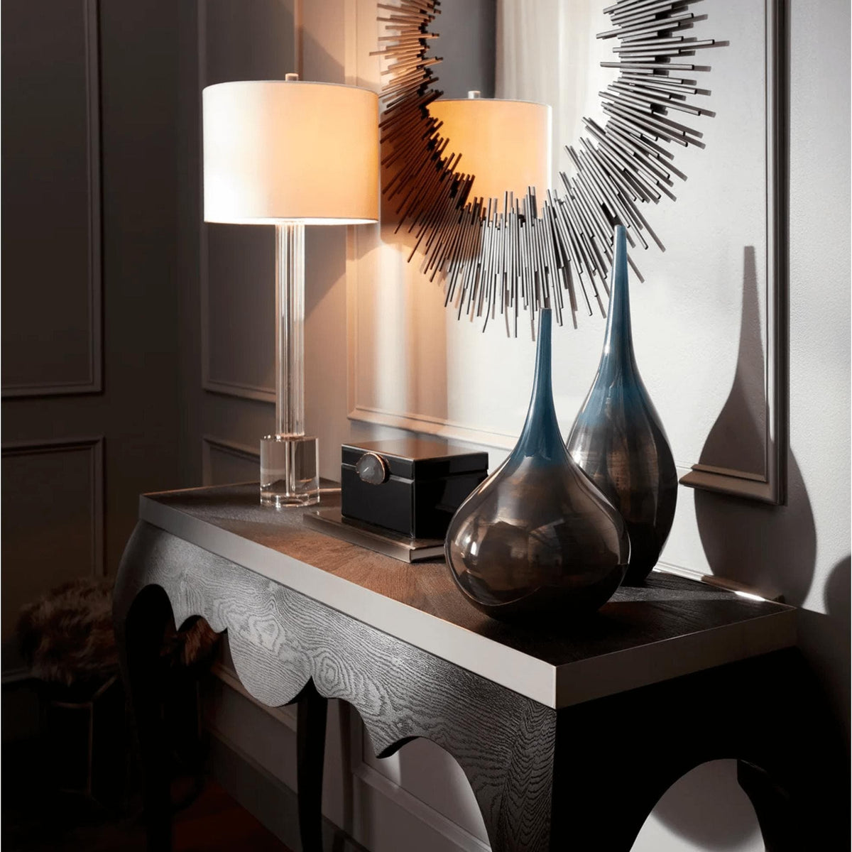 Borealis Graphite Mirror with delicate geometric iron strips, reflecting a modern lamp and vases on a console table.