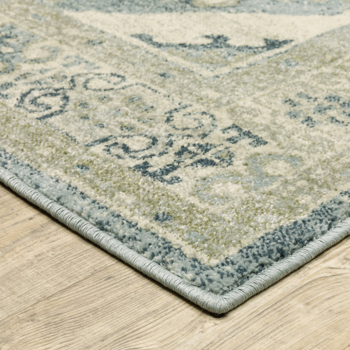Close-up of a Branson Blue & Beige Traditional Rug with intricate patterns on a light wood floor.