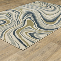 Branson Ivory & Blue Abstract Rug with swirling navy, soft blue, moss green, and neutral tones on a wood floor.