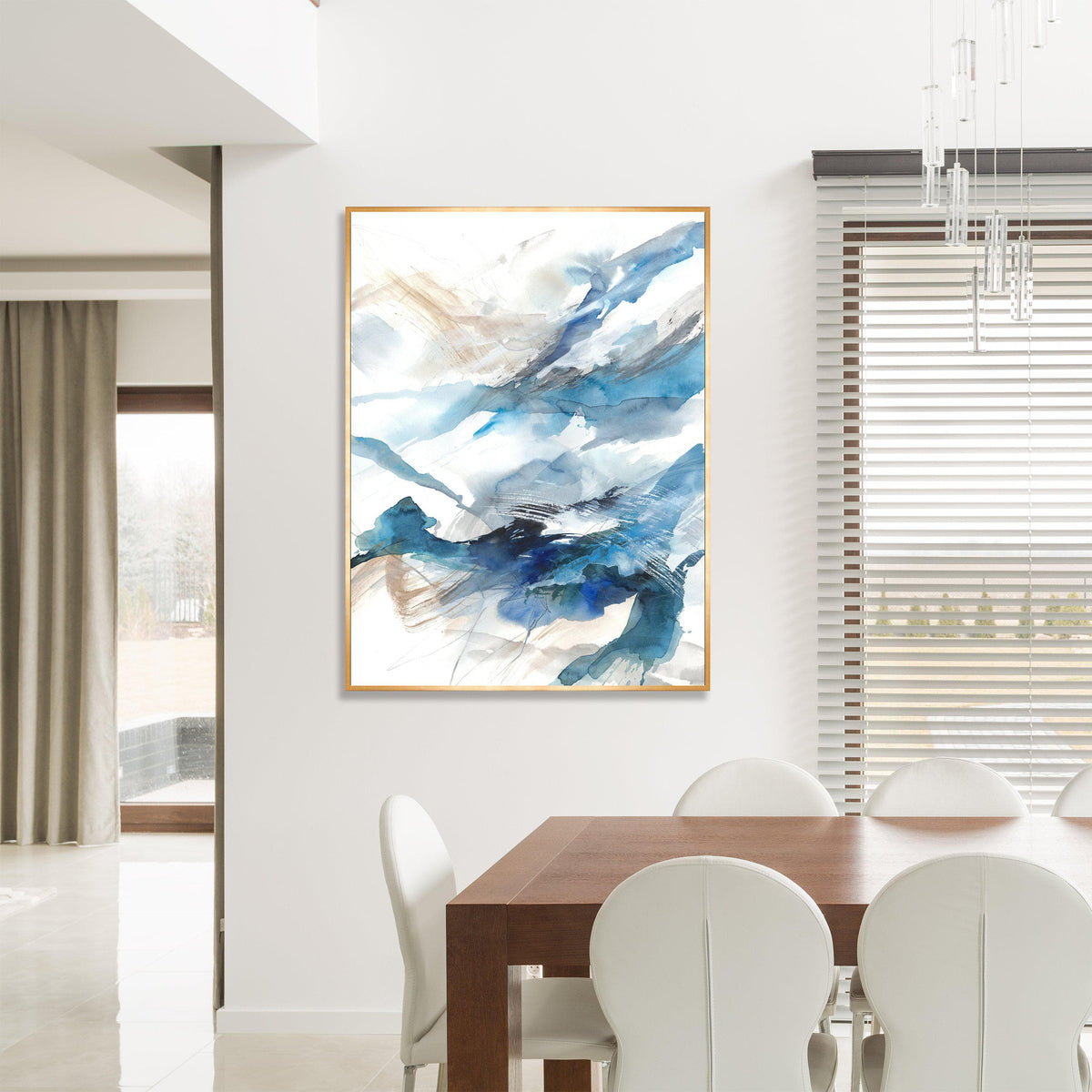 Abstract giclee canvas painting with blue, white, and gold brushstrokes in a gold frame, hanging above a wooden dining table.