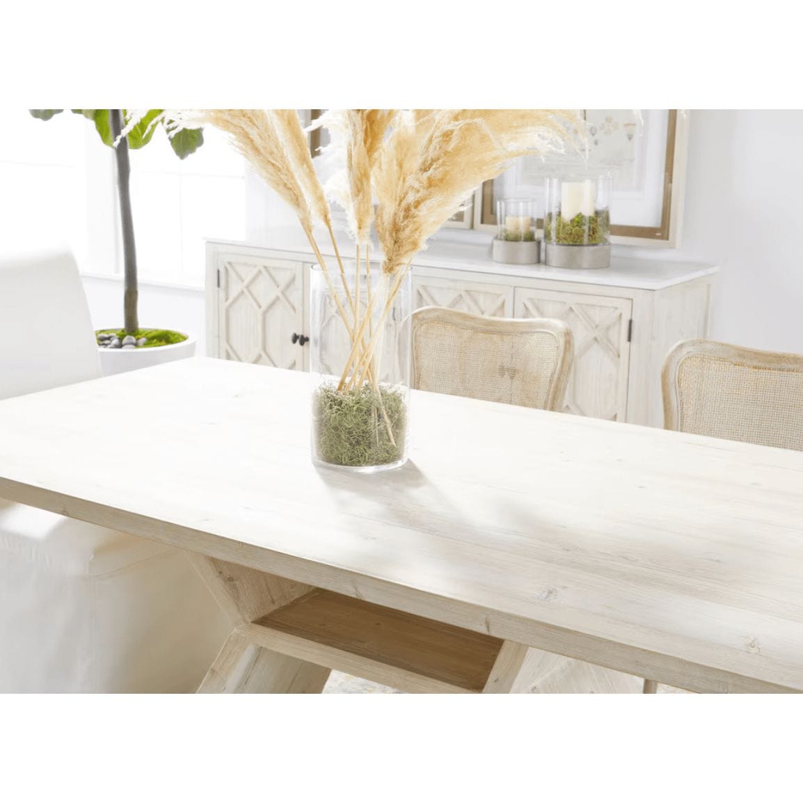Reclaimed wood Bridge Dining Table with white wash finish, angular pedestal base, and pampas grass decor.
