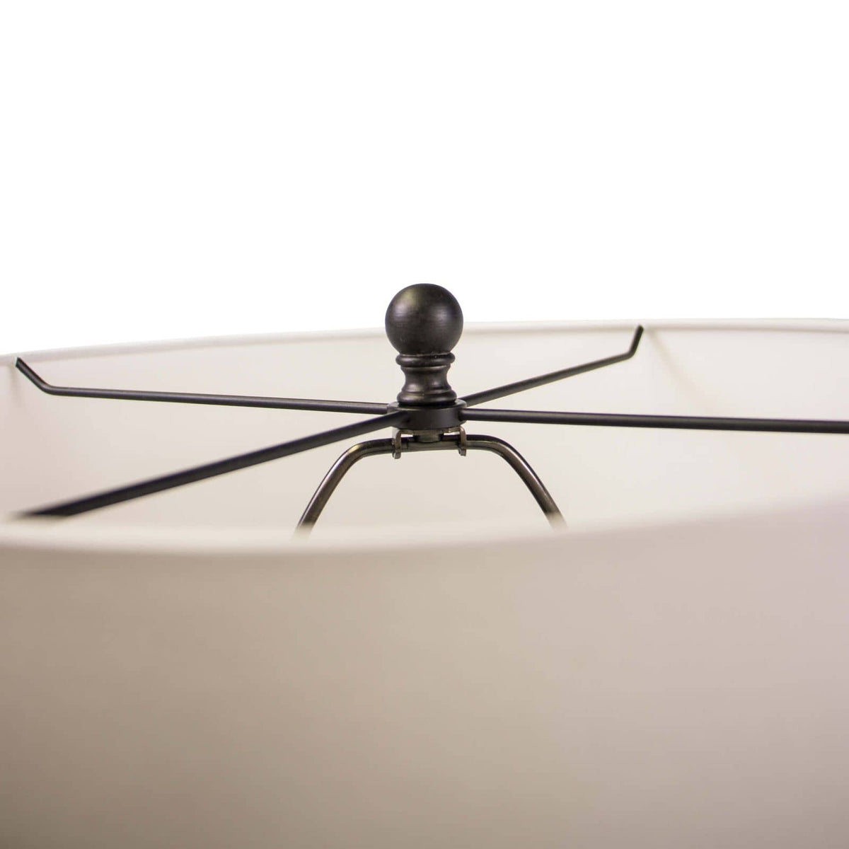 Close-up of a white linen drum shade with a black spider and finial, showing the top of the Buoy floor lamp.