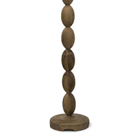 Buoy floor lamp with a stacked birch wood base and a natural linen drum shade, featuring polished brass hardware.