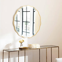 Candice Gold Leaf Mirror with an undulating frame, hanging above a console table.