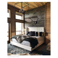 Blackened iron Cape Lantern chandelier with geometric frame and candelabra lights in a rustic bedroom.