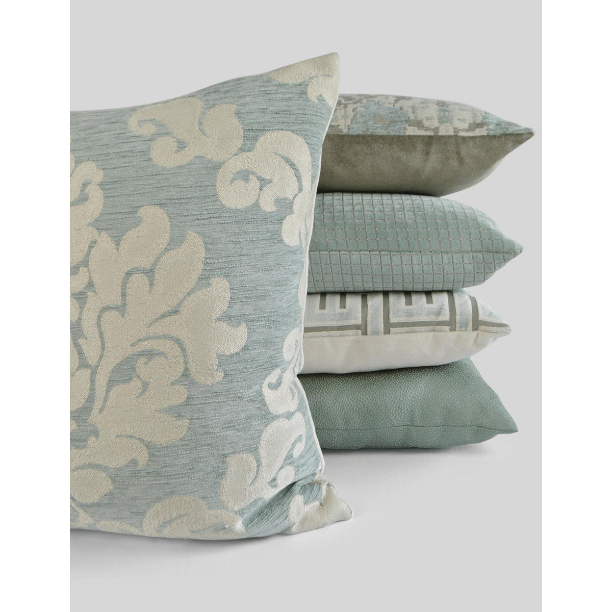 Carlyle Glacier Mist decorative throw pillow, 24x24, with a light blue damask pattern, beside a stack of coordinating pillows.