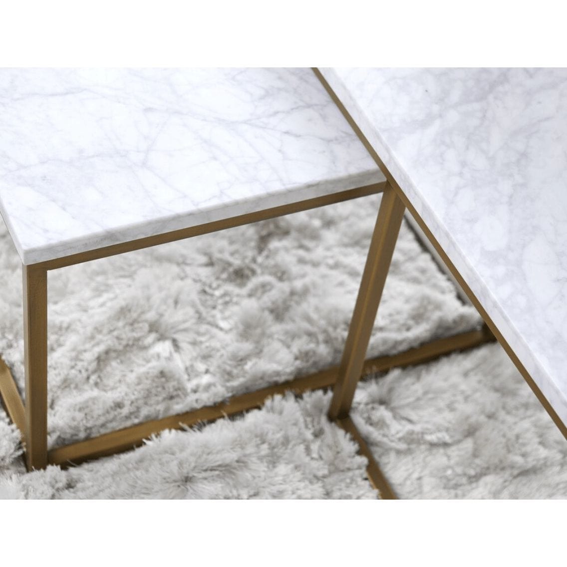 Carrera Nesting Coffee Table with white marble veneer tops and brushed gold steel bases on a fluffy rug.