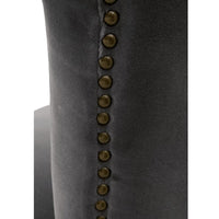 Close-up of a Celina Dark Dove velvet dining chair, showing the dark gray upholstery and decorative brass nailhead trim.
