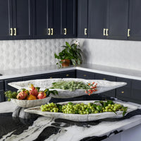 Three whitewashed Ardu wood decorative bowls on a marble counter, filled with fruit and greenery.