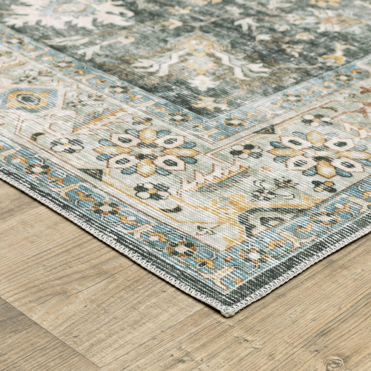 Charleston Charcoal & Gold Washable Rug with distressed traditional patterns on a wood floor.
