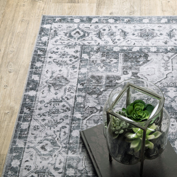 Charleston Charcoal & Ivory washable rug with distressed traditional patterns on light wood flooring.