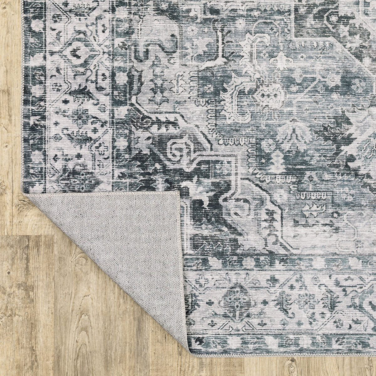 Charleston Charcoal & Ivory Washable Rug with distressed traditional patterns and non-slip backing on wood floor.